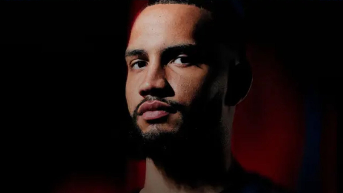 A determined basketball player with a focused expression, dribbling a ball on a modern indoor basketball court with dramatic lighting.