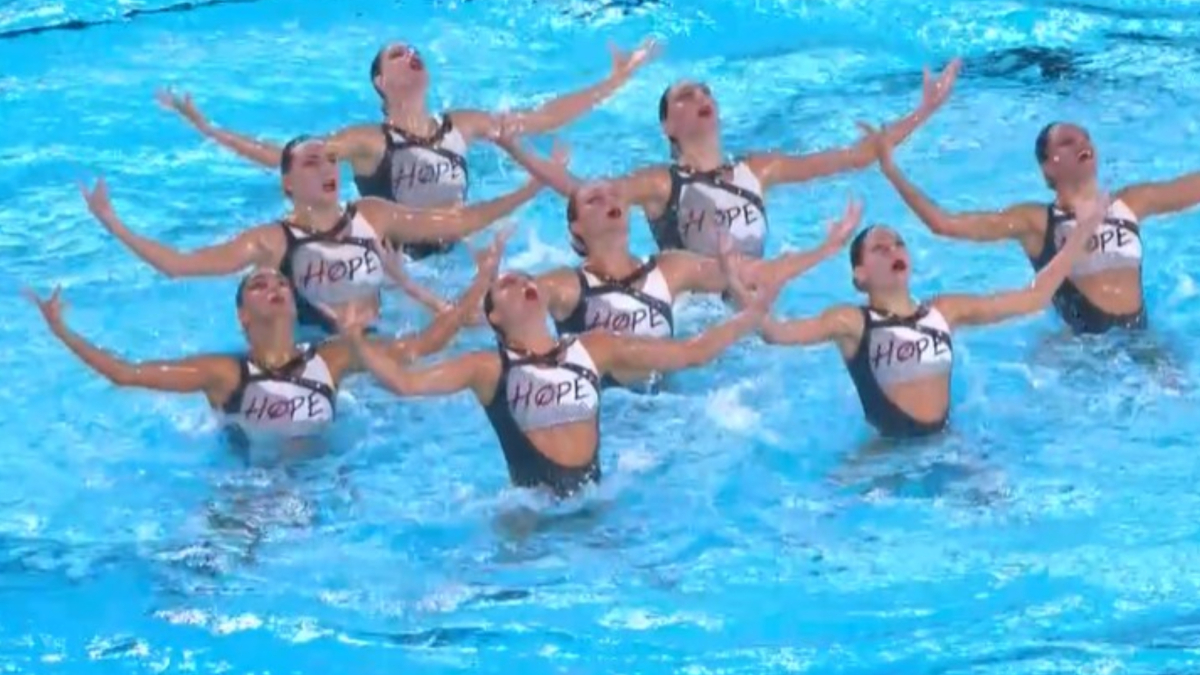 Atlete spagnole in piscina durante una gara di nuoto artistico, con abiti con la parola Hope