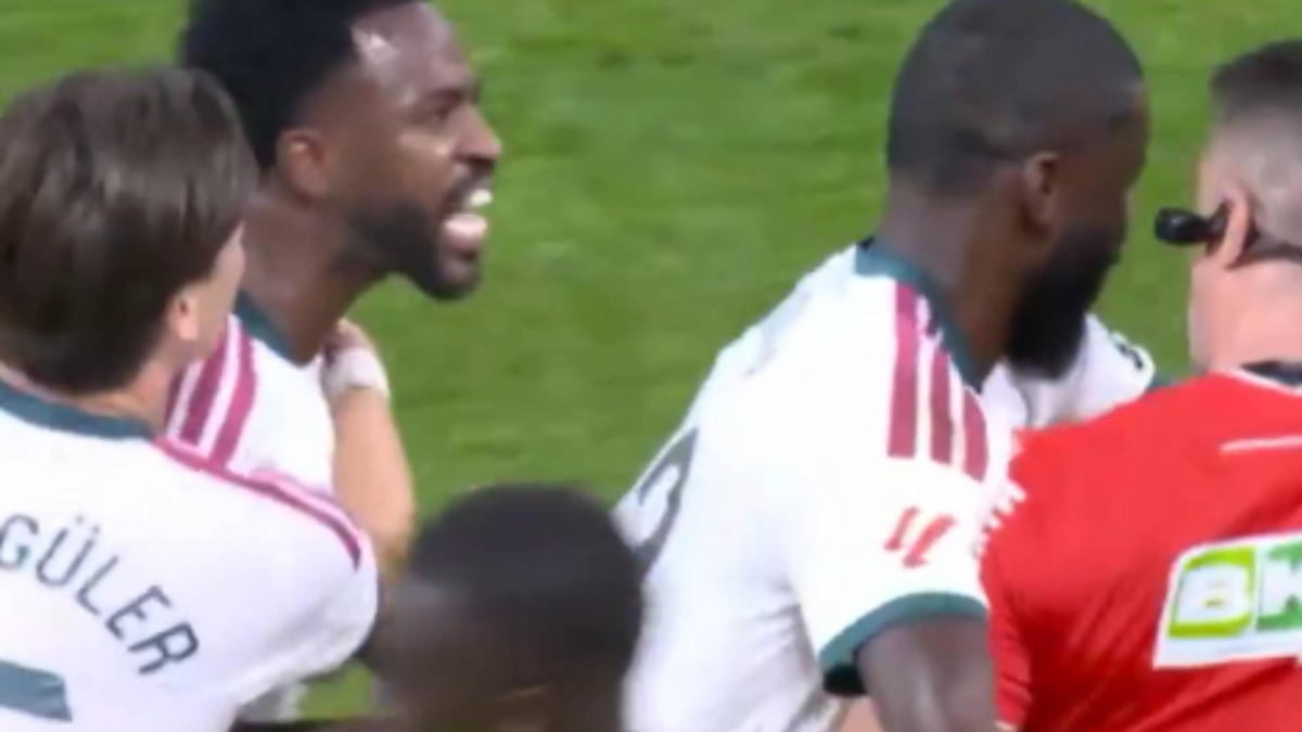 Vinicius Junior gestures angrily at referee Díaz de Mera while Real Madrid teammates try to hold him back after seeing a red card during the match against Villarreal.