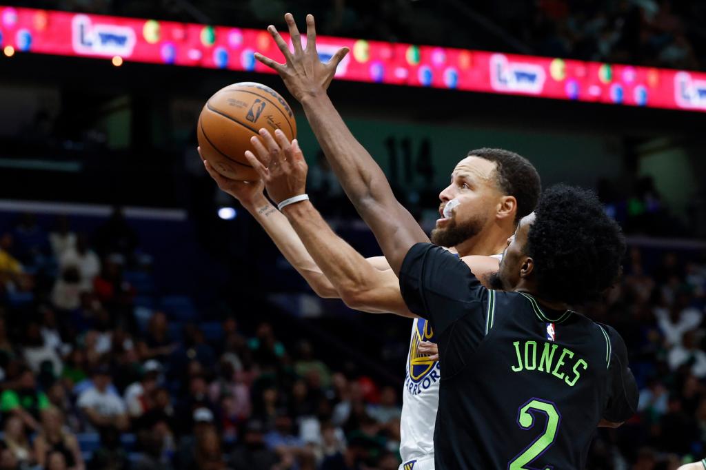 Stephen Curry intenta llegar a dejar una bandeja presionado por Herbert Jones.