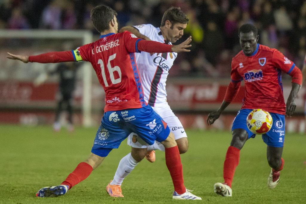 El delantero del RCD Mallorca, Abdón Prats (c), disputa el balón ante el jugador del Numancia, Carlos Gutierrez.