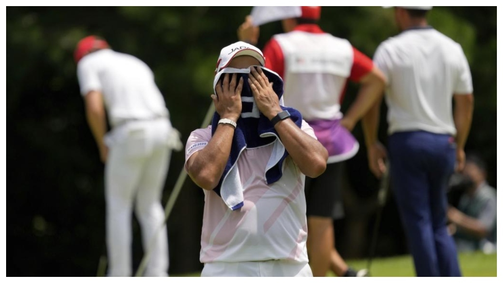 Hideki Matsuyama se seca el sudor, mientras al fondo Xander Schauffele patea.