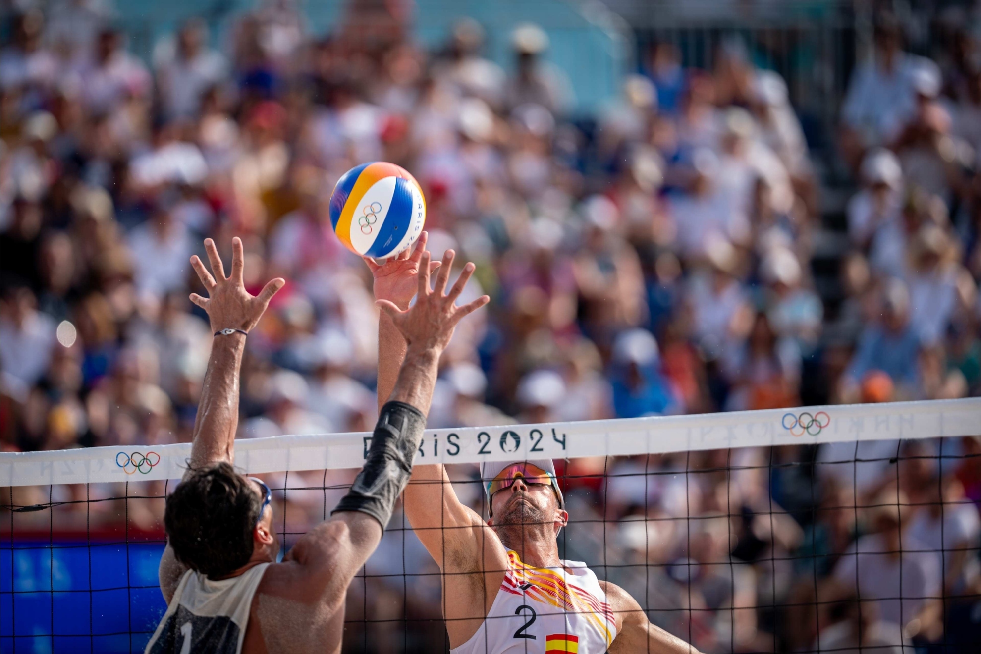 Adrián Gavira golpeando la pelota frente al bloqueo del francés Youssef Krou en París 2024