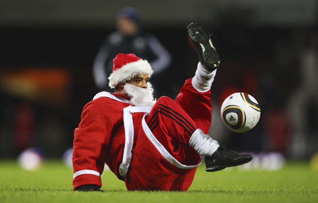 Un aficionado disfrazado de Papá Noel da toques durante un partido.