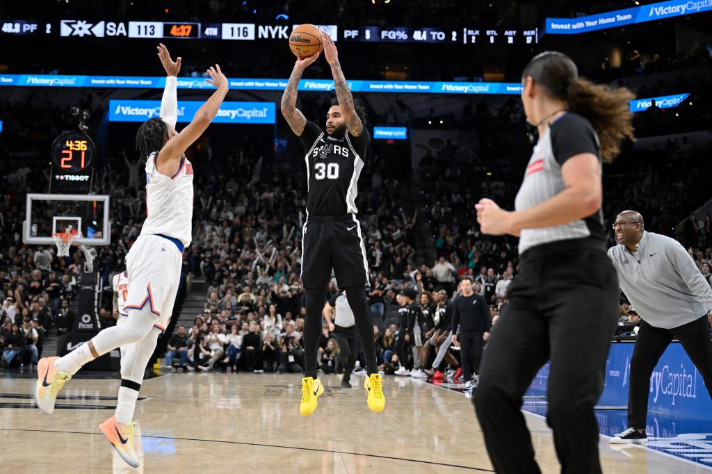 Julian Champagnie lanza un triple defendido por Jalen Brunson.