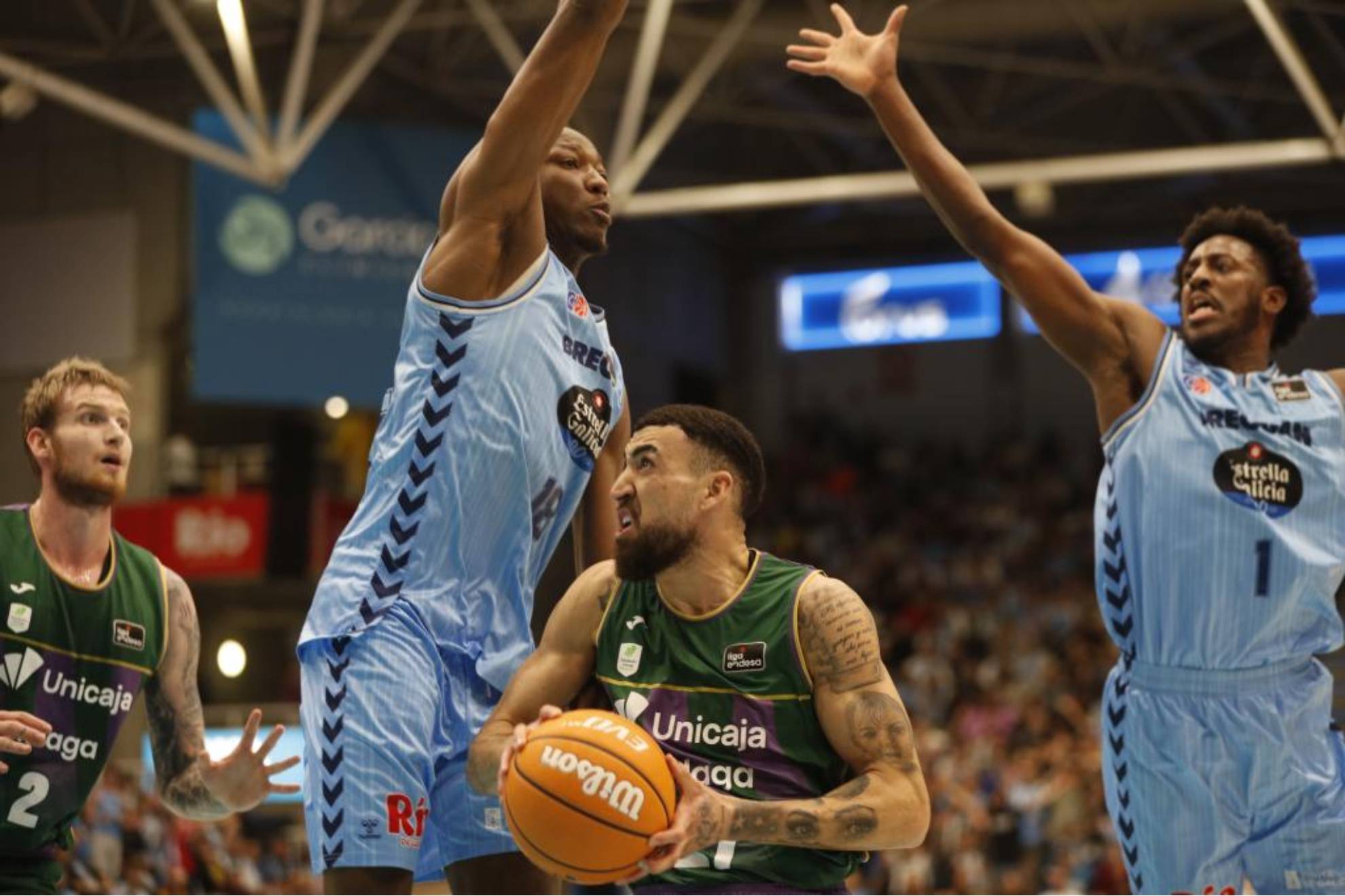 El alero dominicano del Unicaja Málaga, Chris Duarte, rodeado de rivales del Breogán.