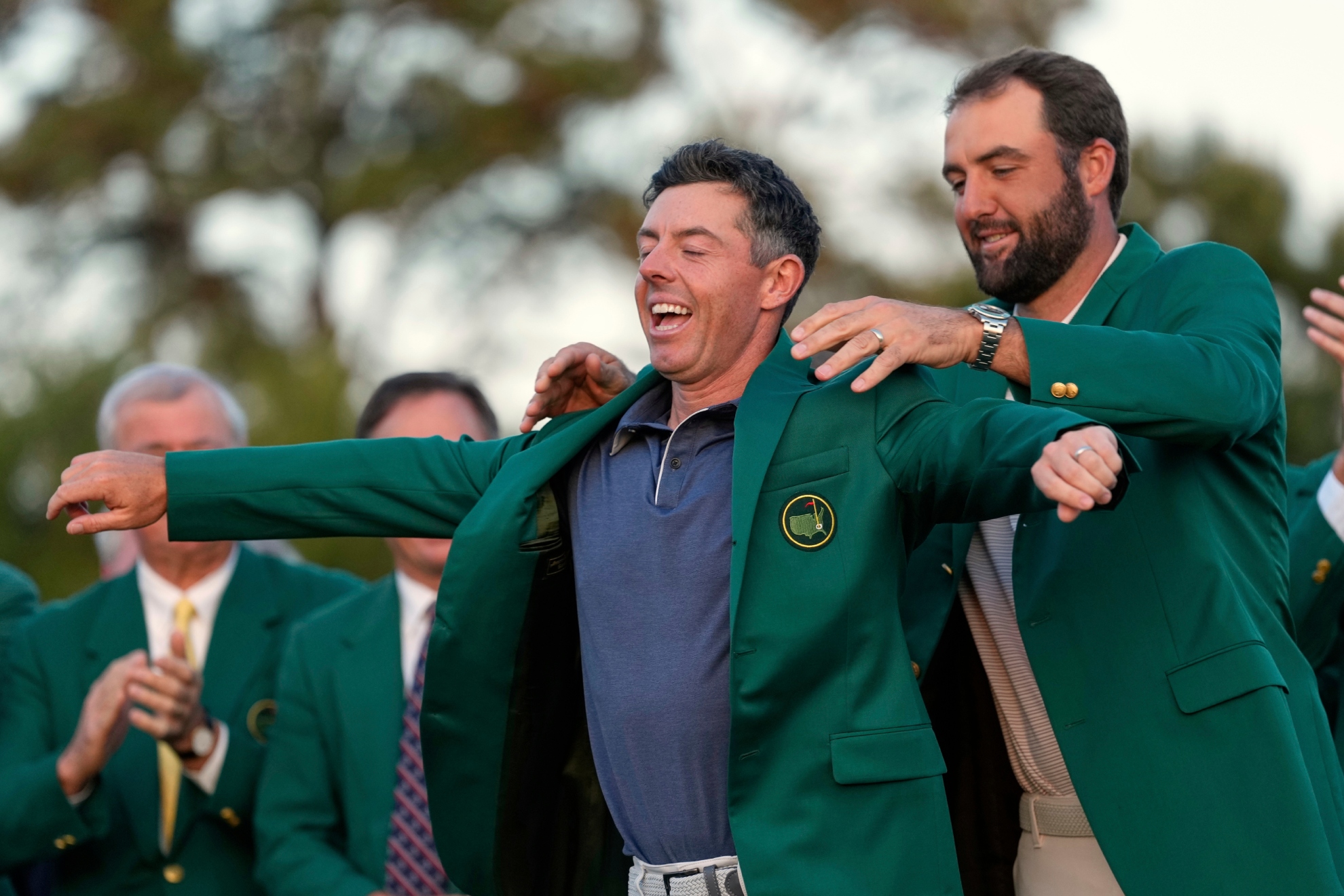 Rory McIlroy tras ganar este año, es ayudado por Scheffler a enfundarse la chaqueta verde.
