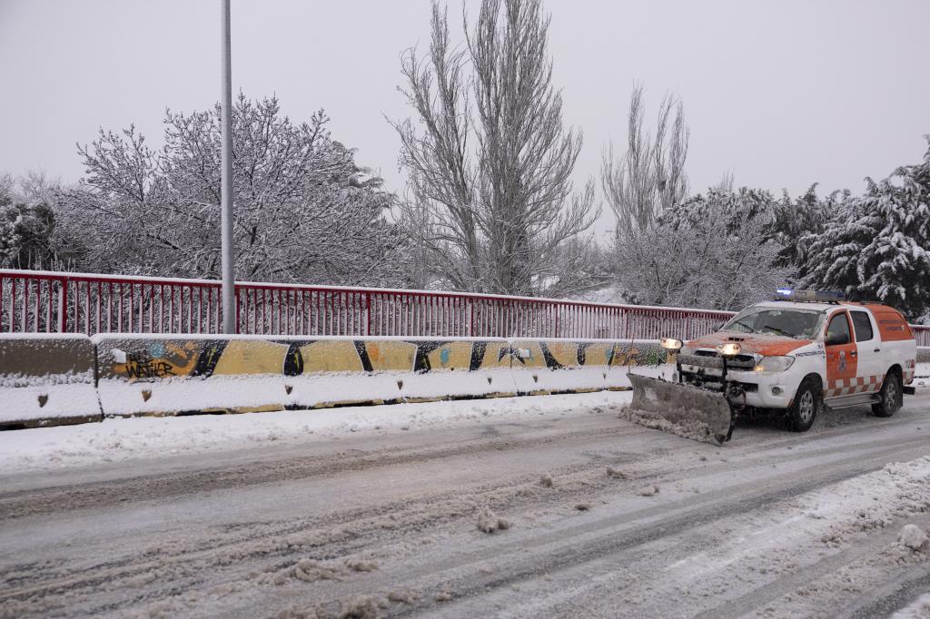 Un vehículo de Protección Civil con una pala quitanieves limpia en una carretera en Alpedrete.