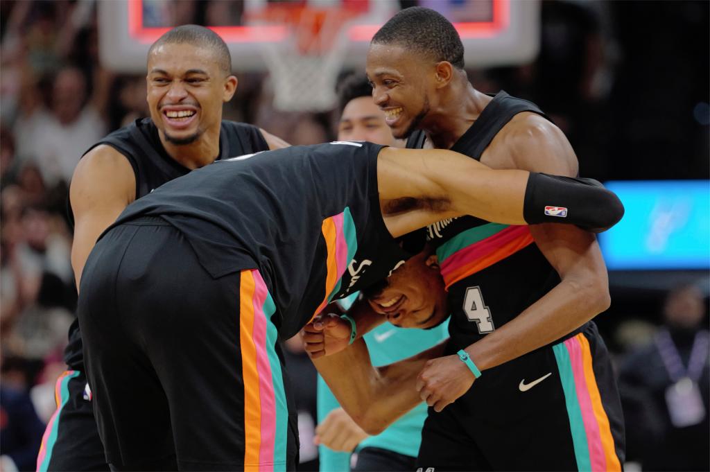 Victor Wembanyama es abrazado por sus compañeros tras ganar un partido.