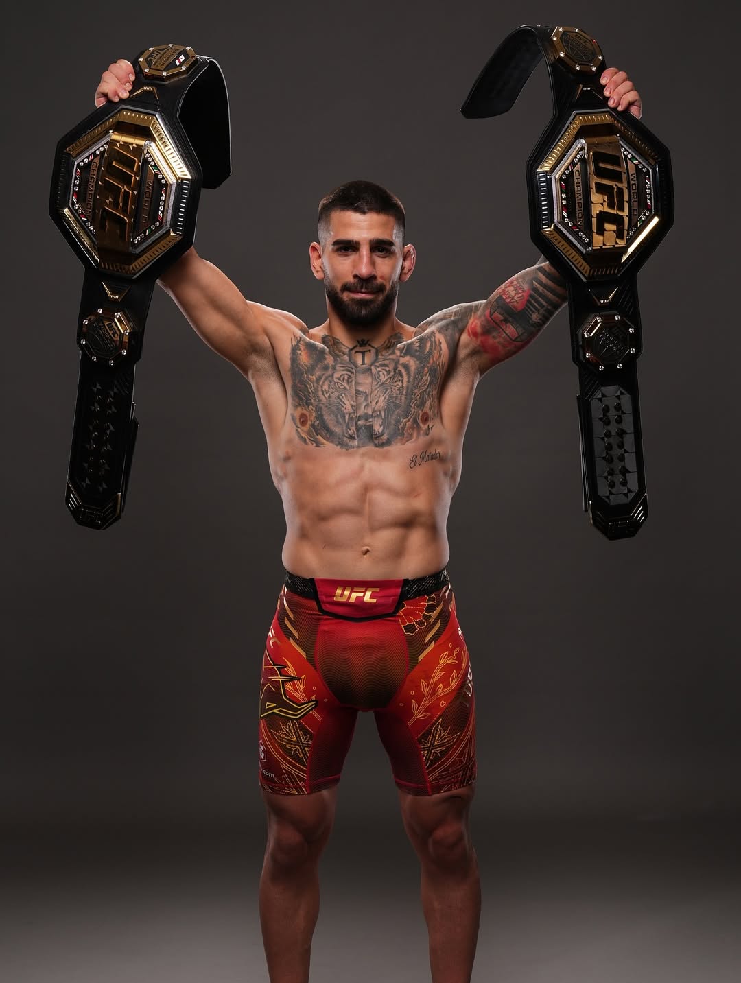 Ilia Topuria poses with her two UFC champion titles.
