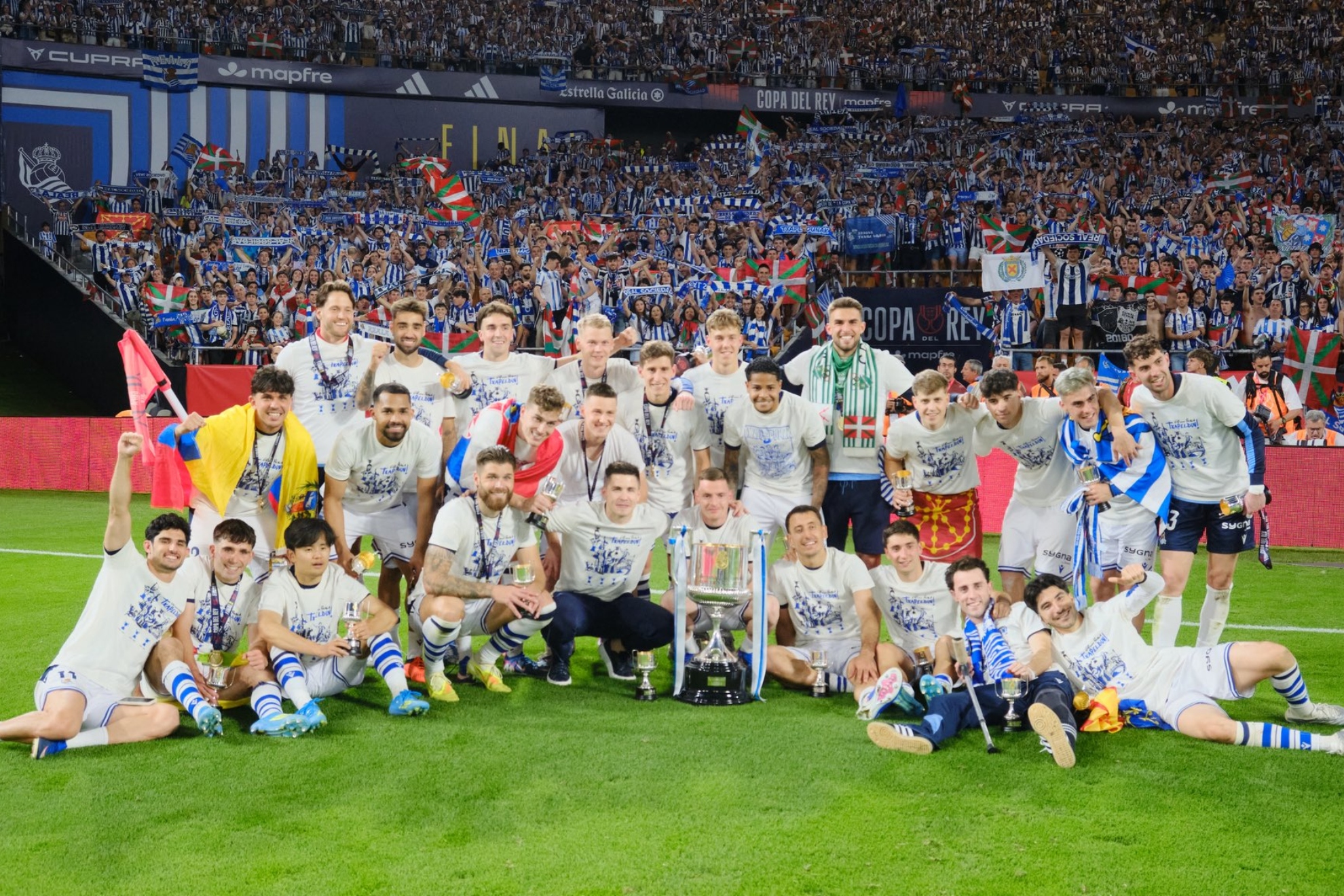 Los futbolistas de la Real posan con la Copa en el fondo de La Cartuja donde estuvo su afición.