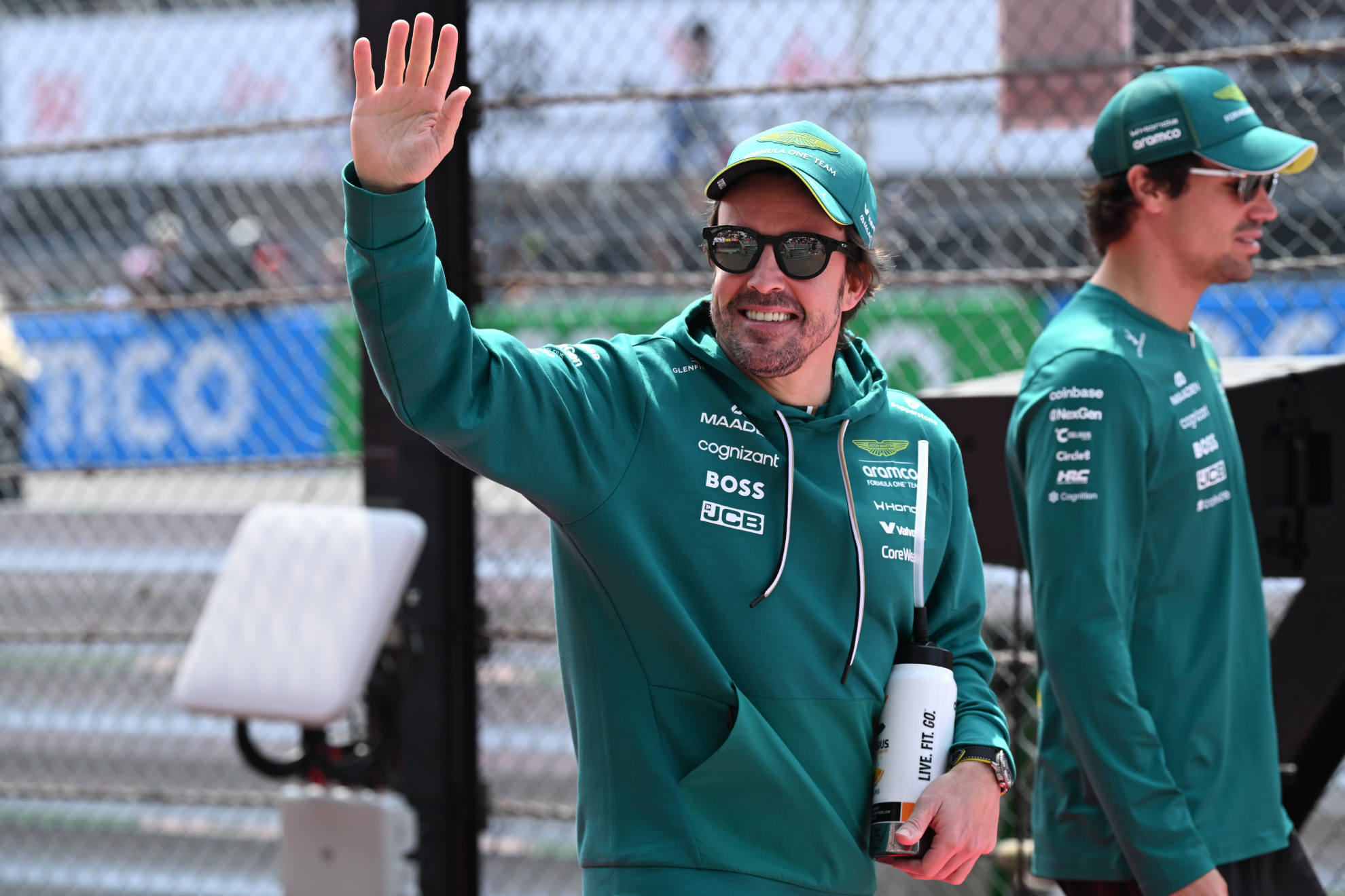 Fernando Alonso se gira para saludar, mientras camina al lado de Lance Stroll.