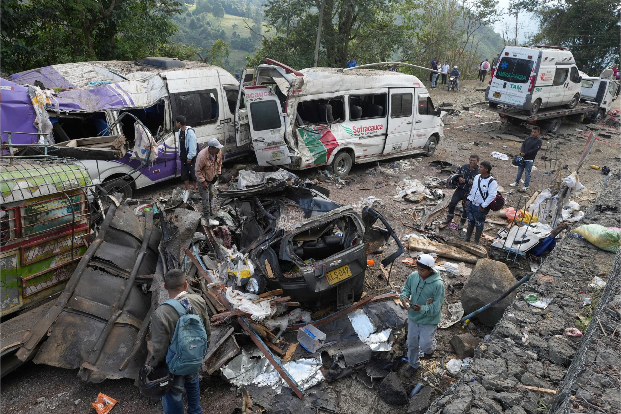Personas observan este domingo vehículos destruidos por un atentado ocurrido en la Vía Panamericana en Cajibío (Colombia).
