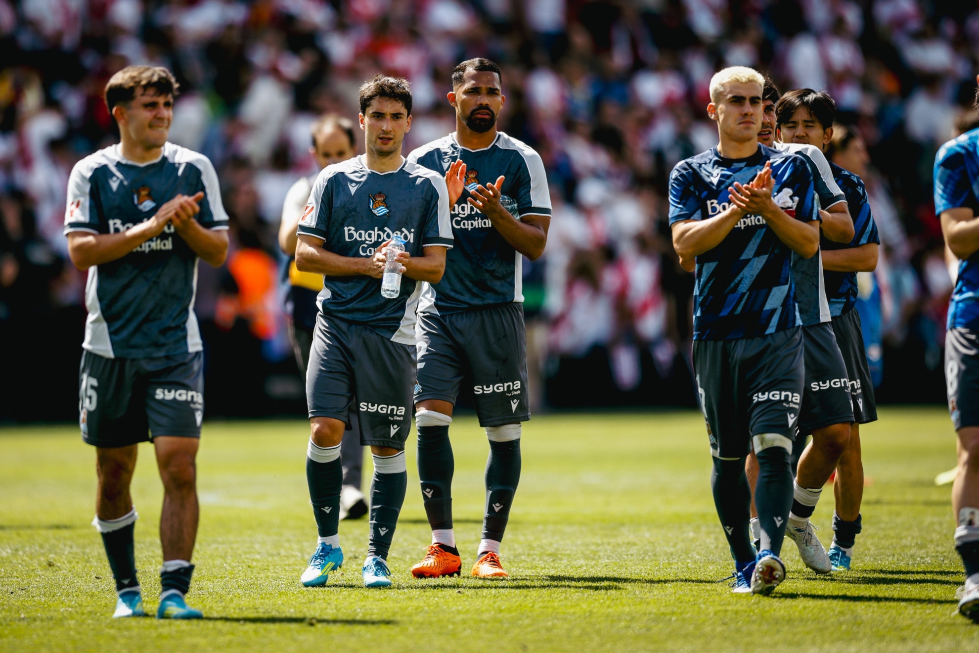 Varios realistas aplauden a la afición txuriurdin presente en Vallecas, tras el partido.