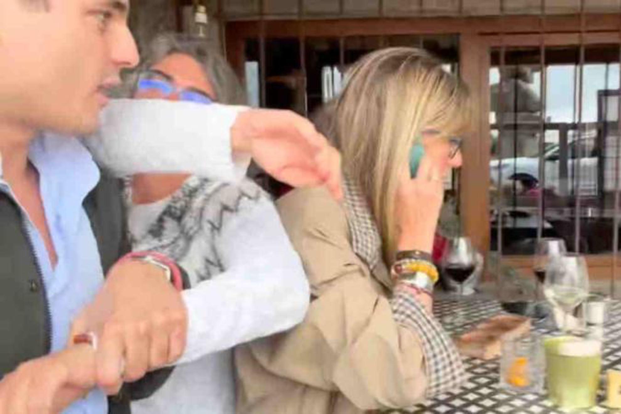 Vito Quiles, intentando hablar con Begoña Gómez mientras una mujer trata de impedirlo.