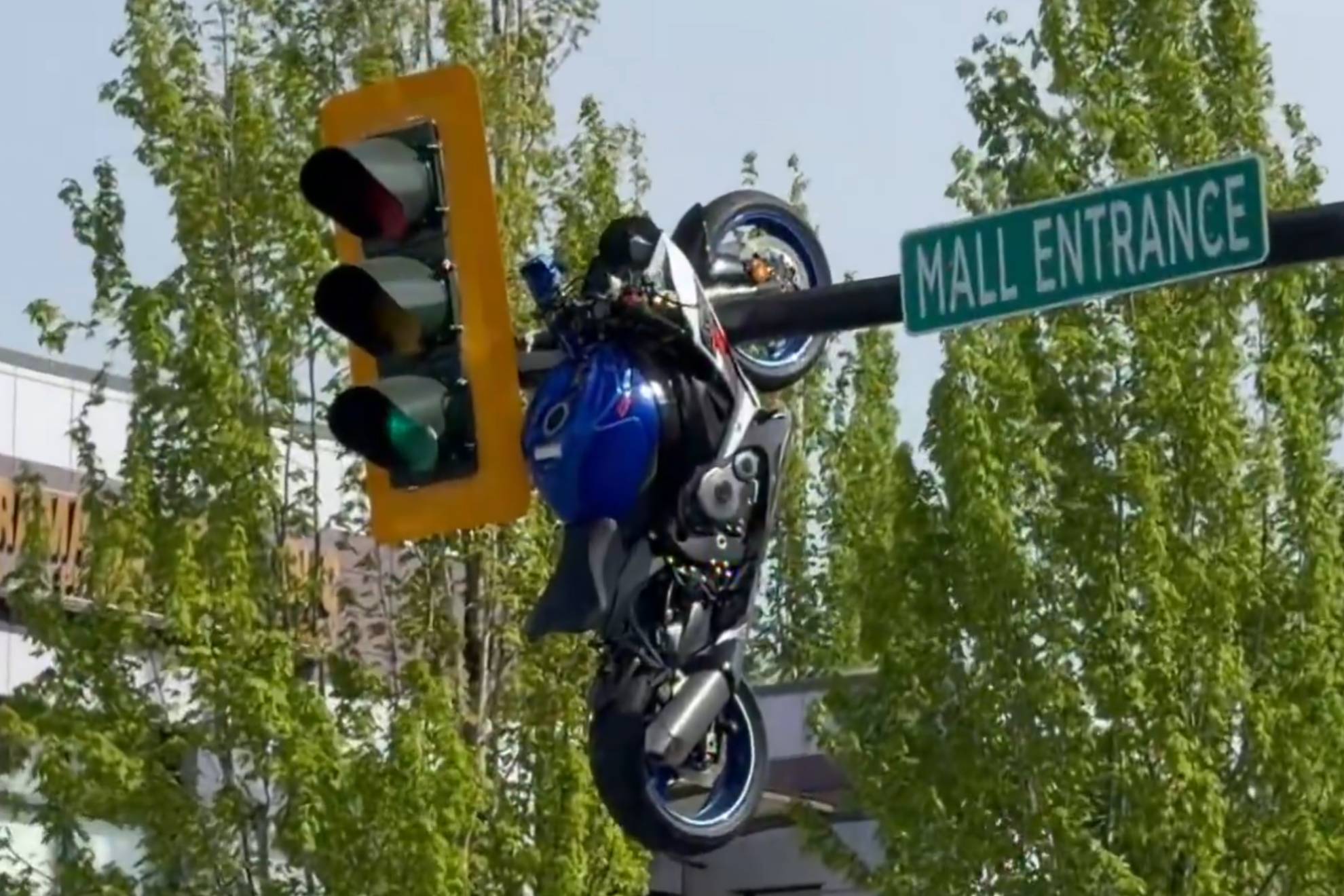 La moto, sujeta del semáforo por la horquilla y la rueda delantera.
