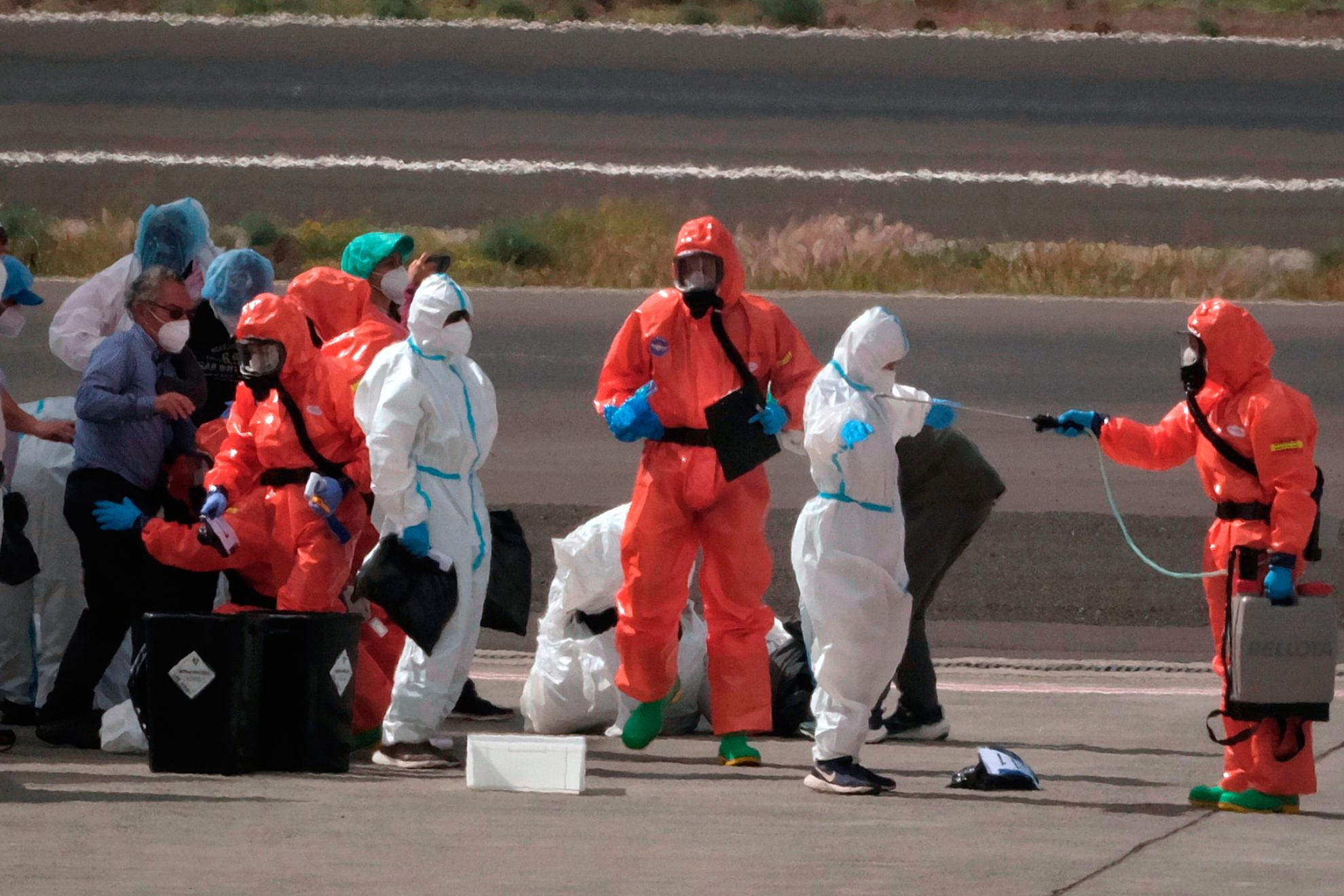 Pasajeros son rociados con desinfectante tras desembarcar del crucero MV Hondius en Tenerife.