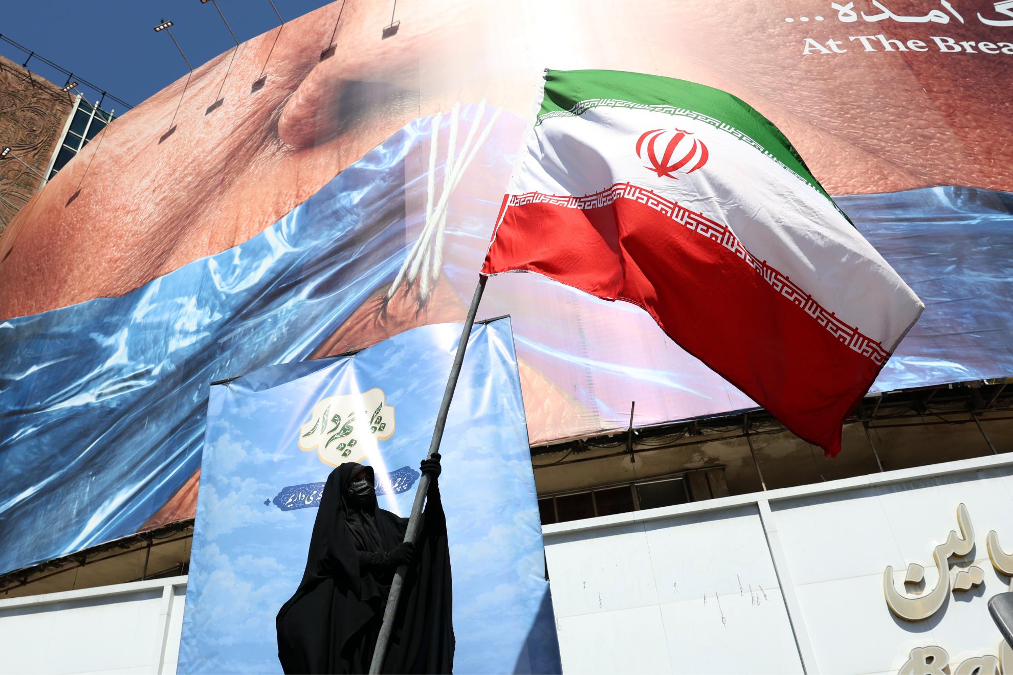 Una mujer ondea una bandera de Irán en una calle de Teherán.