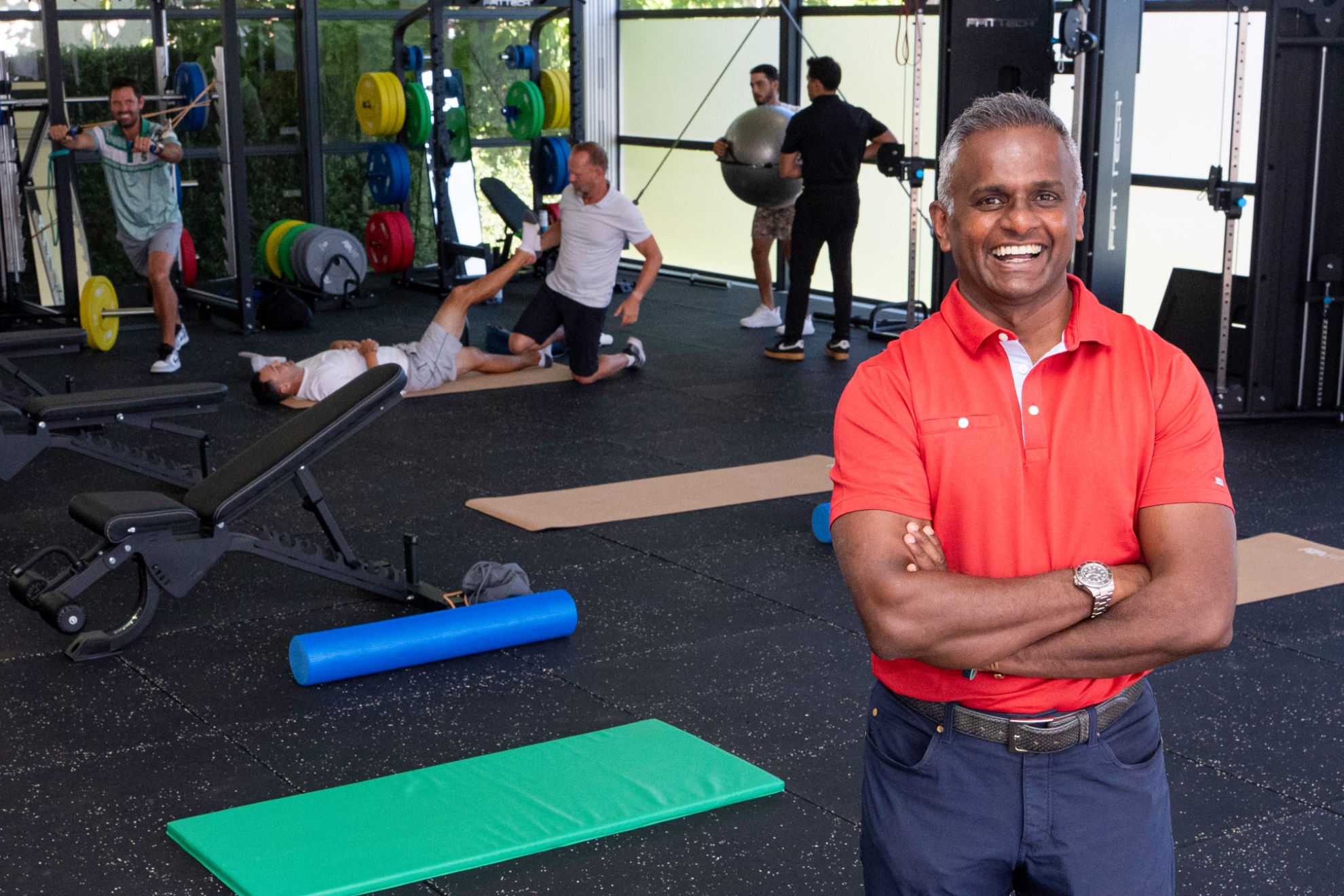 El doctor doctor Ara Suppiah posa en el APC de LIV Golf con algunos jugadores de fondo.