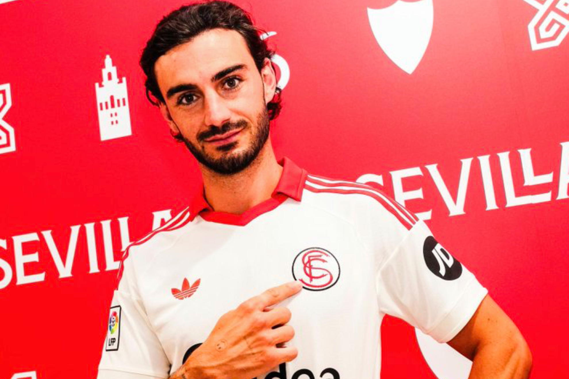 Juan Iglesias señala el escudo del Sevilla en su camiseta.
