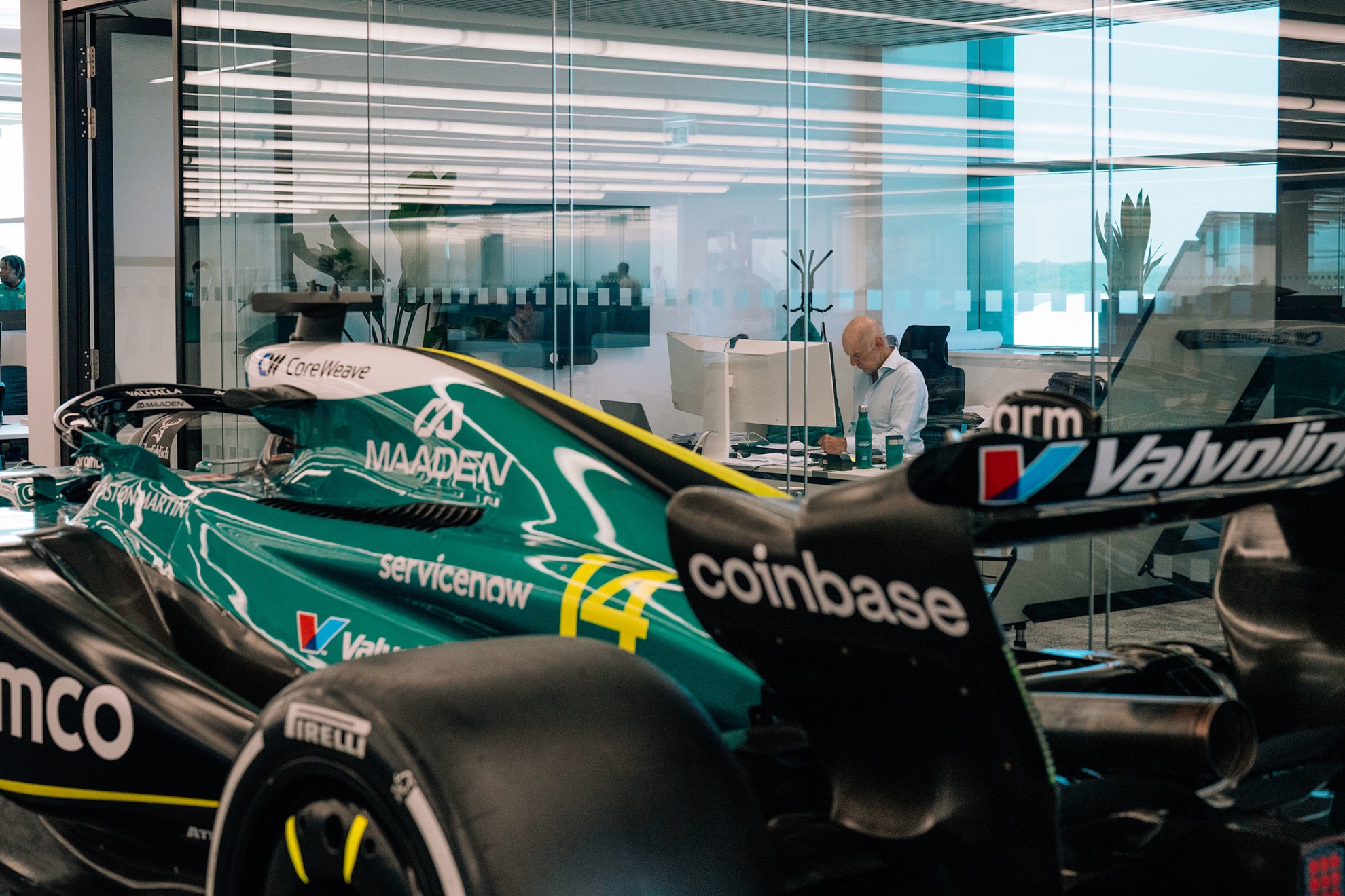 Newey trabaja en su oficina con un Aston Martin a su lado.