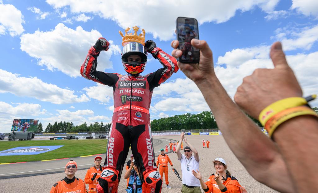 El español Marc Márquez celebra su victoria con una corona en la cabeza después del Gran Premio de Moto GP de Alemania, en Sachsenring en Hohenstein-Ernstthal, Alemania, el domingo 12 de julio de 2026. (Robert Michael/dpa vía AP)
