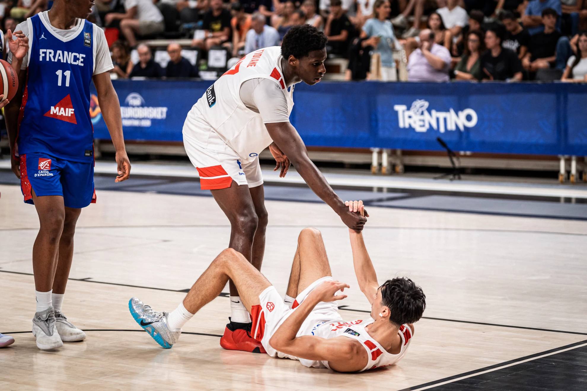 Chiek Diallo ayuda a levantarse a Humberto Ruiz. FIBA