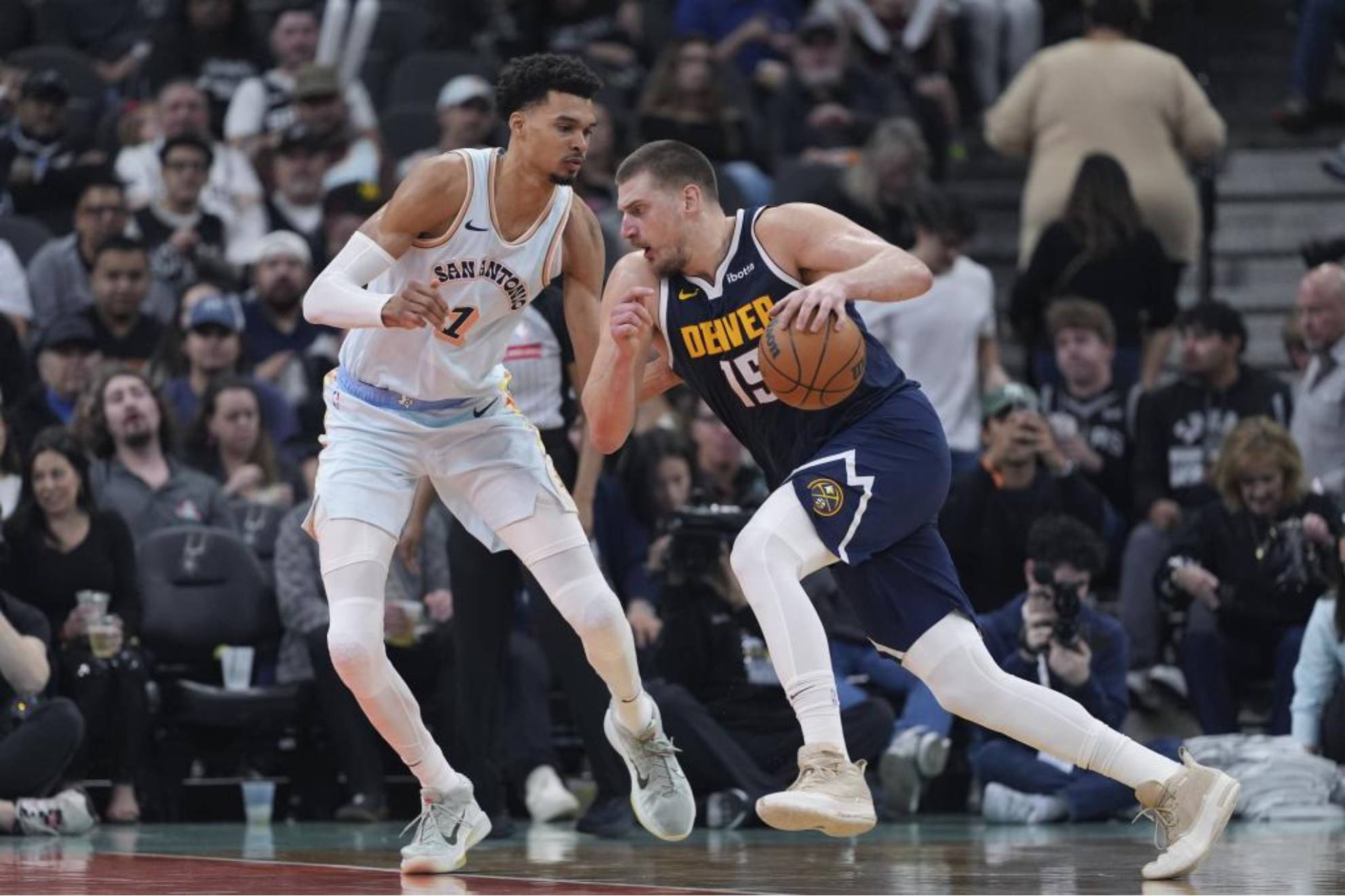 Jokic intentando superar la defensa de Wembanyama en un Nuggets-Spurs de la NBA.