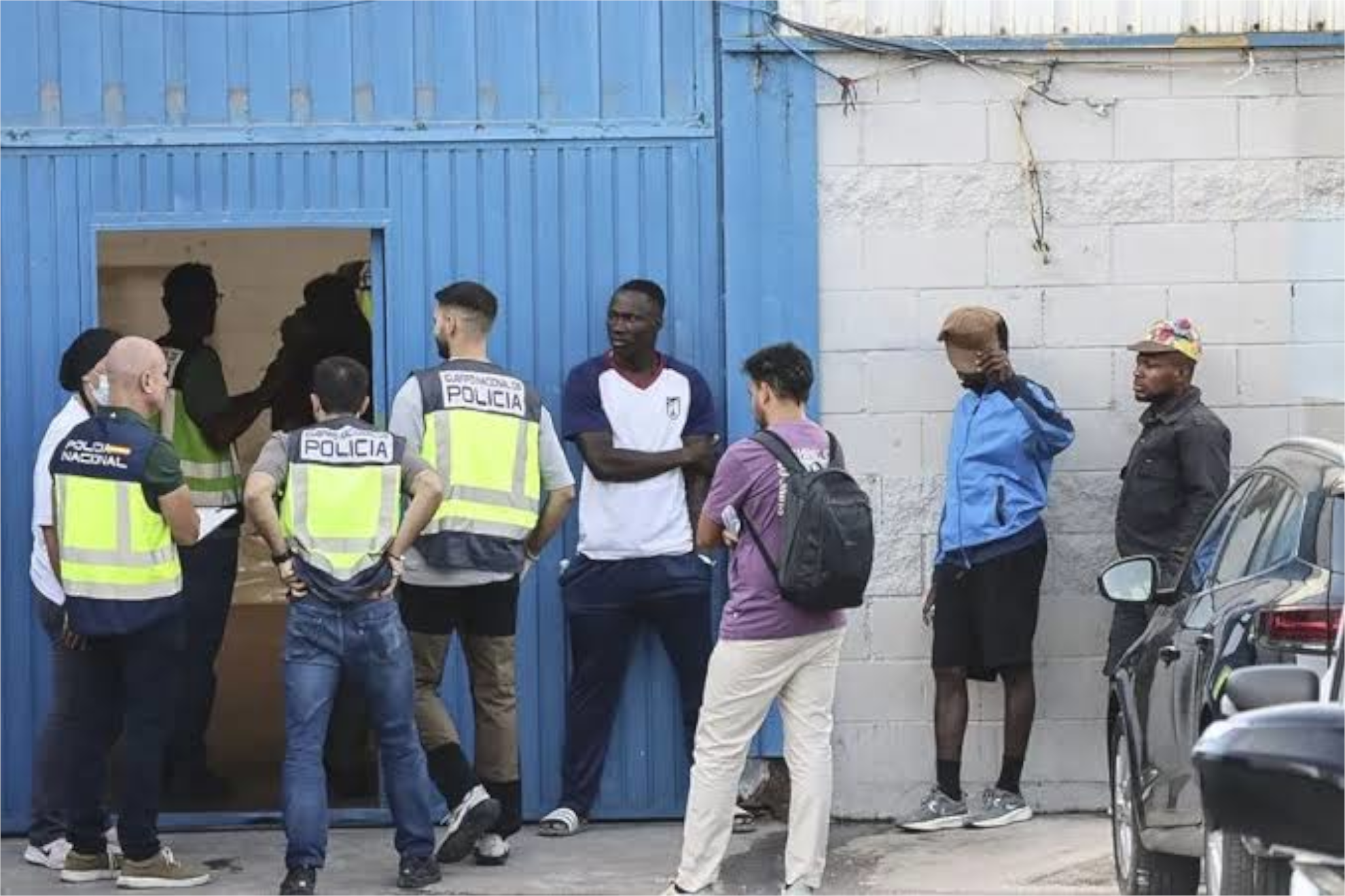 Agentes de Policía y migrantes en la puerta de una nave del Tarajal, este miércoles EFE