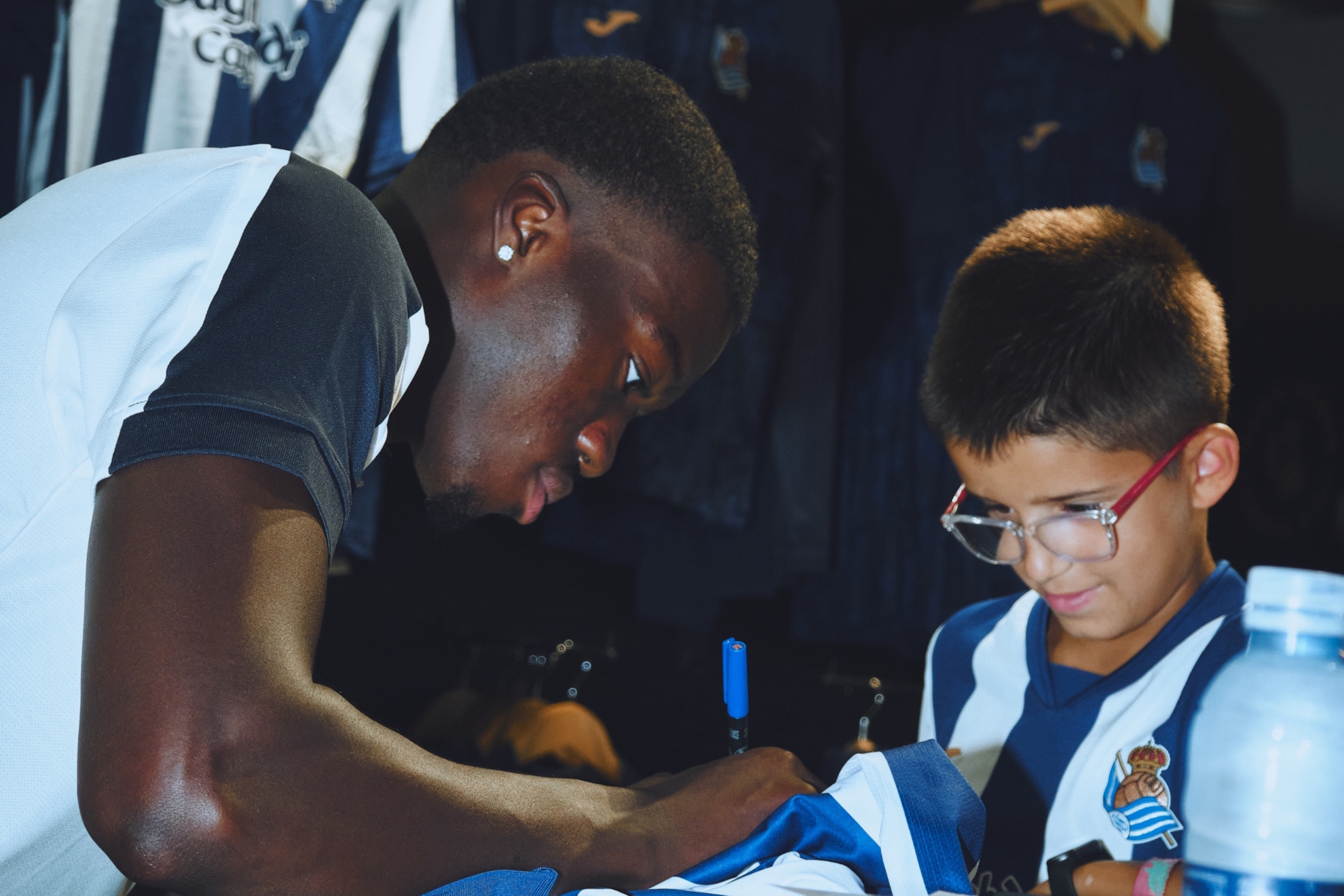 Mamadou Sarr firma una camiseta a un joven seguidor de la Real, tras su presentación. REAL SOCIEDAD