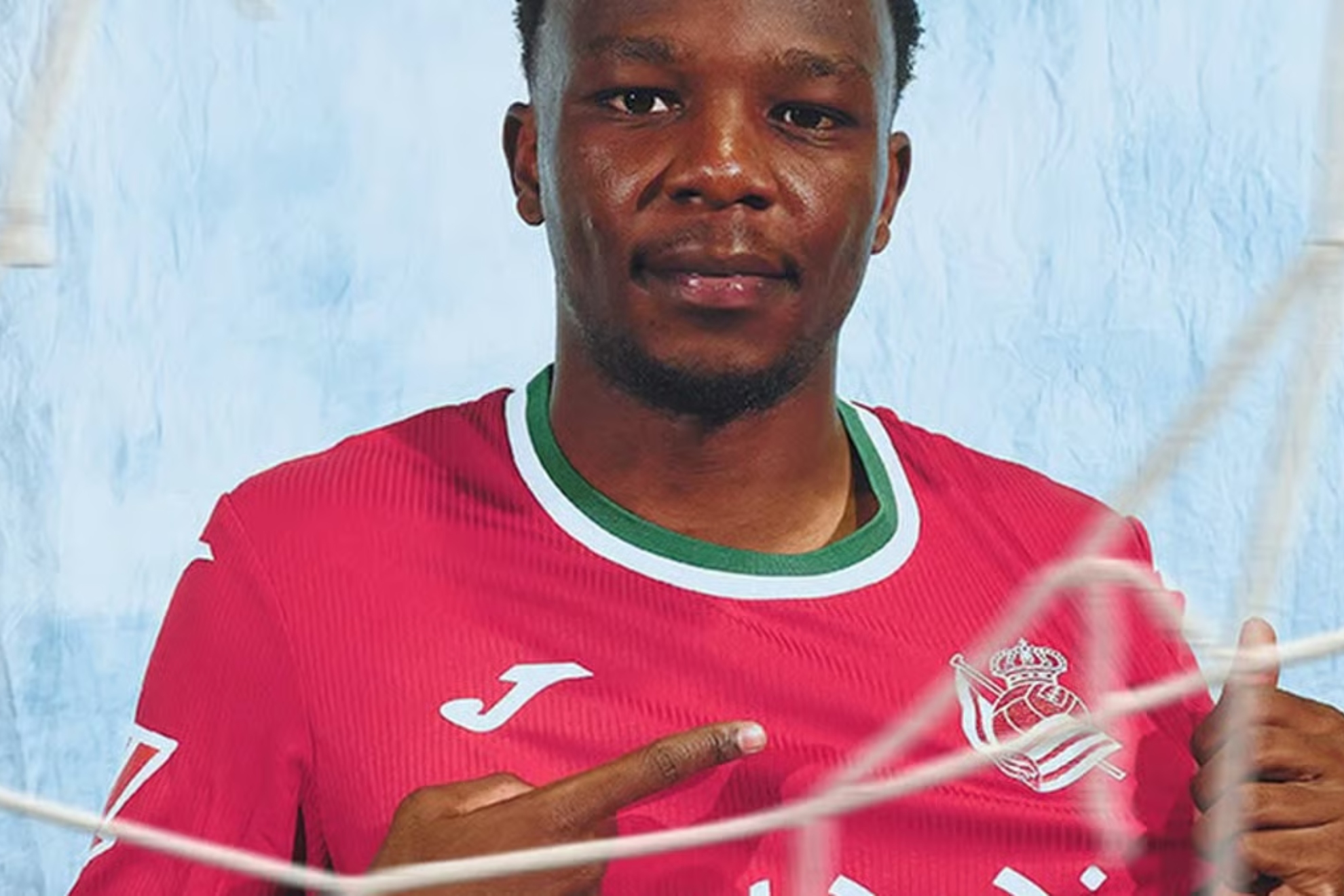 Job Ochieng posa con la camiseta roja de la Real. REAL SOCIEDAD