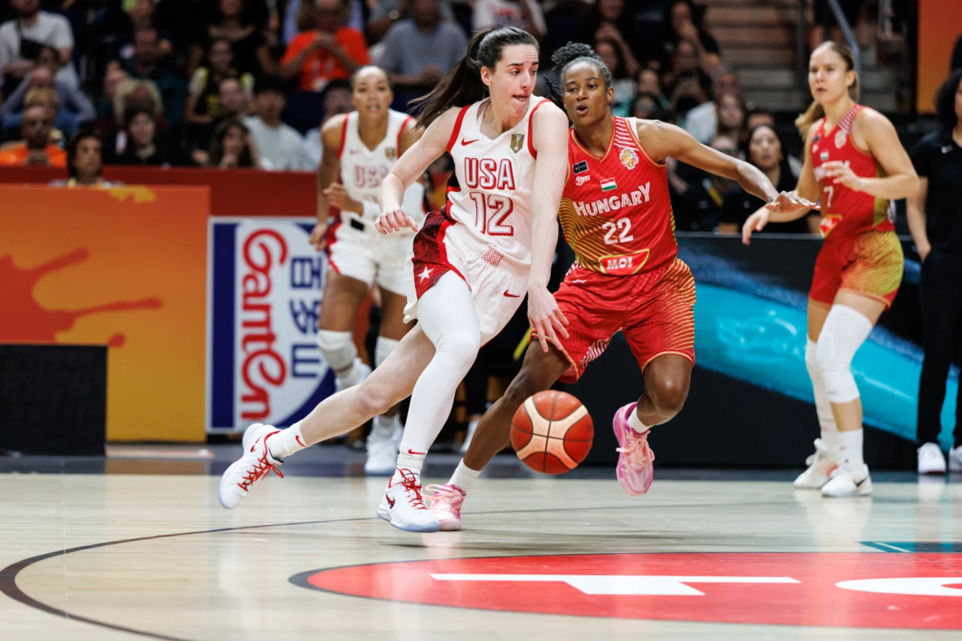 Caitlin Clark bota el balón en presencia de Yvonne Turner. FIBA PHOTO.