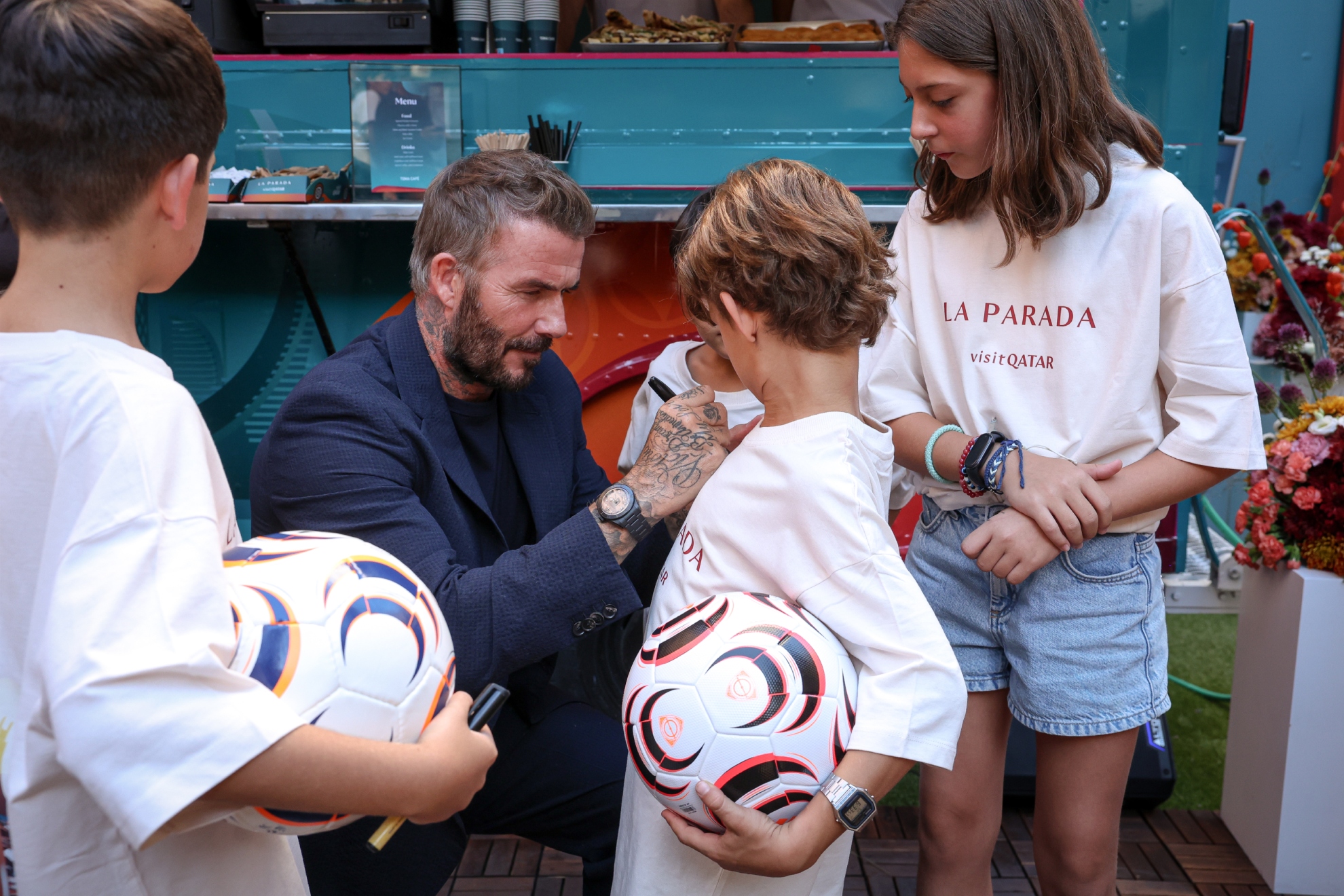 Beckham firma a los niños en La Parada de Visit Qatar.