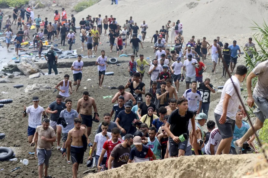 Migrantes caminan por una playa de Ceuta