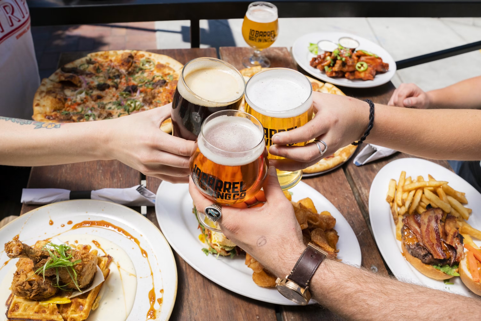 Imagen de recurso de varias personas brindando con su cerveza y comida. Pixabay.