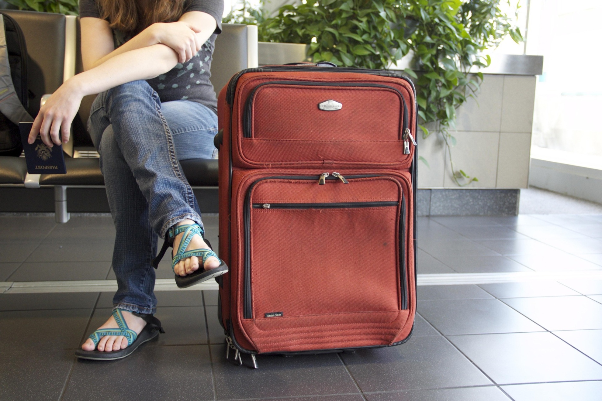 Imagen de una persona en un aeropuerto sentada con su maleta. Pixabay.