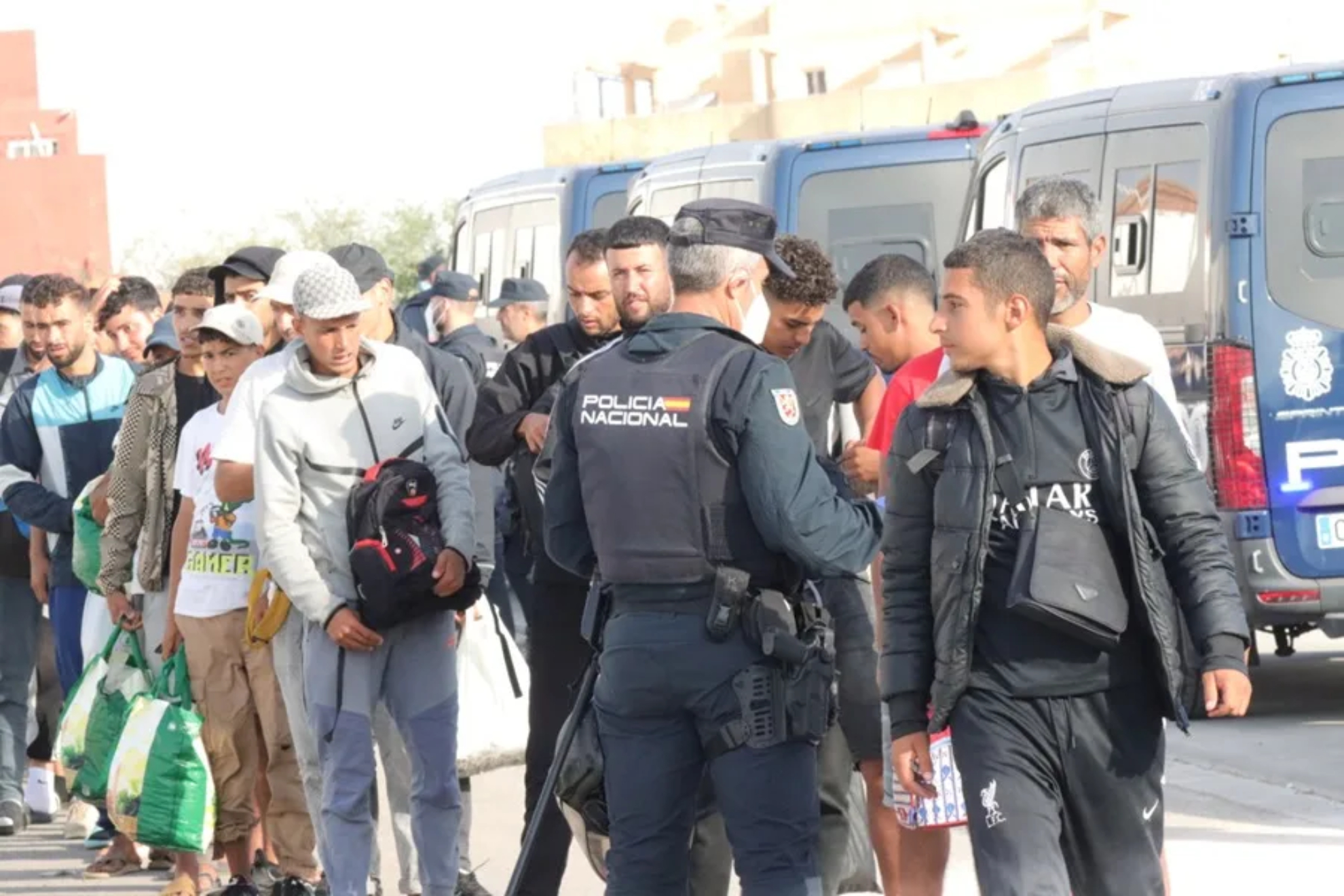 Policia junto migrantes en Ceuta EFE