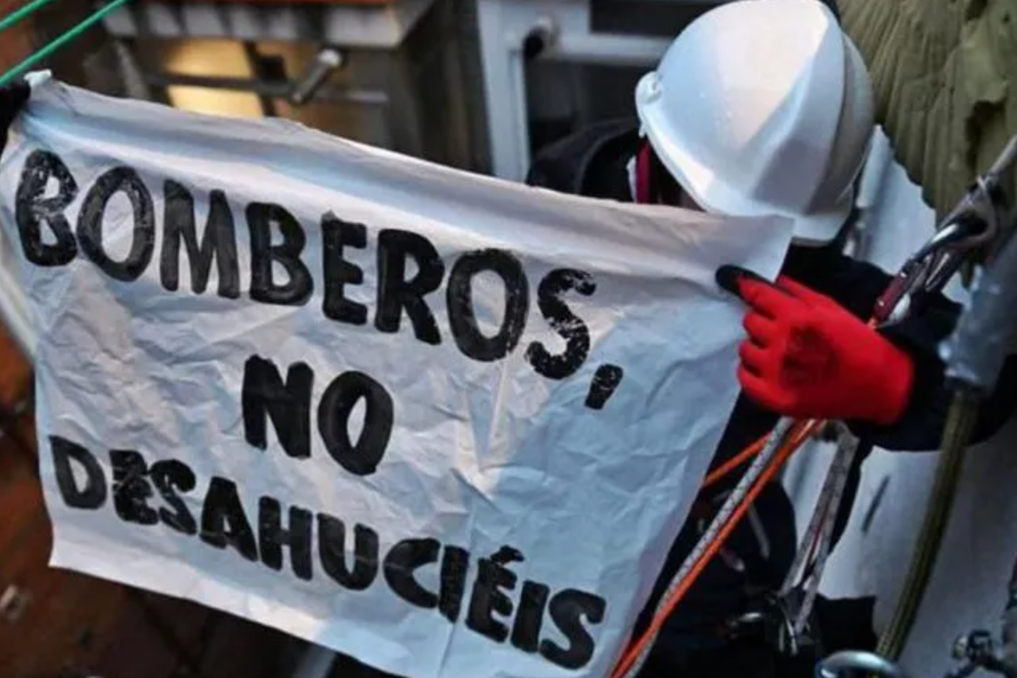 Militante del movimiento de vivienda descolgado por la fachada para evitar el desahucio de un vecino de Vallecas. Bomberx contra Desahucios
