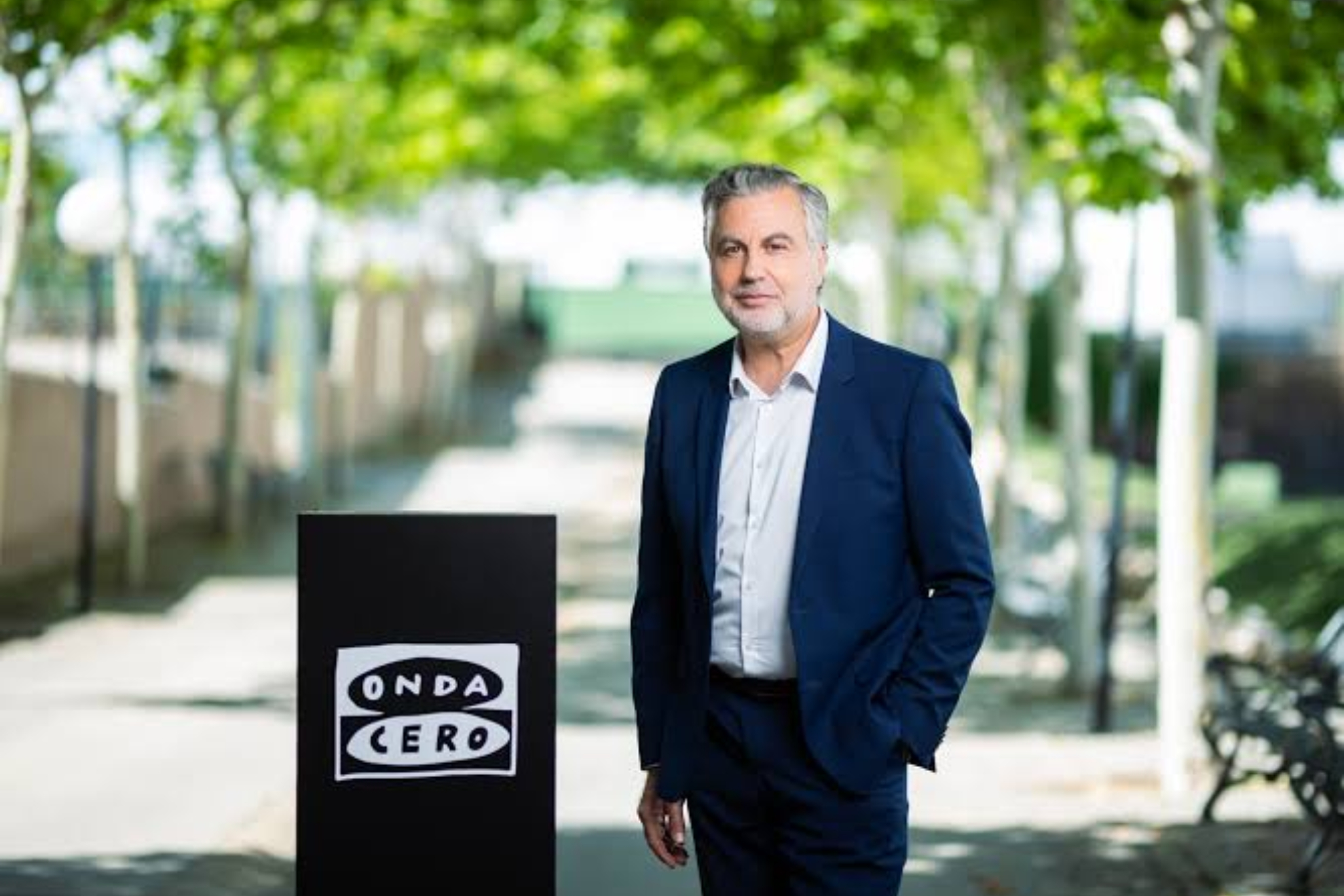 Carlos Alsina junto el logo de Onda Cero Atresmedia