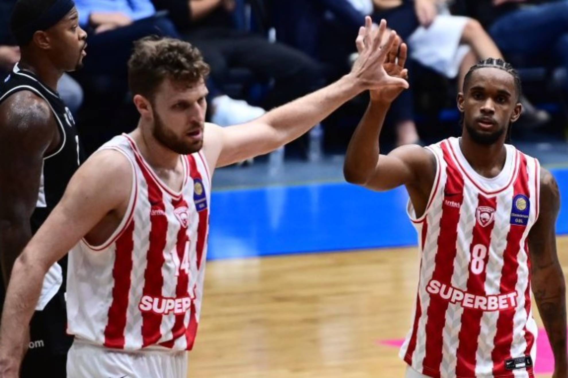 Sasha Vezenkov y Jean Montero se saludan durante un partido del Olympiacos. .